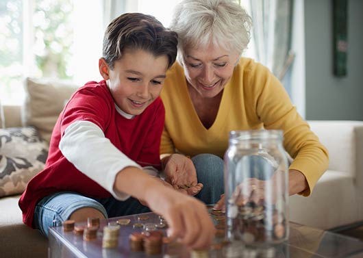 Grandmother and grandson saving coins in a jar